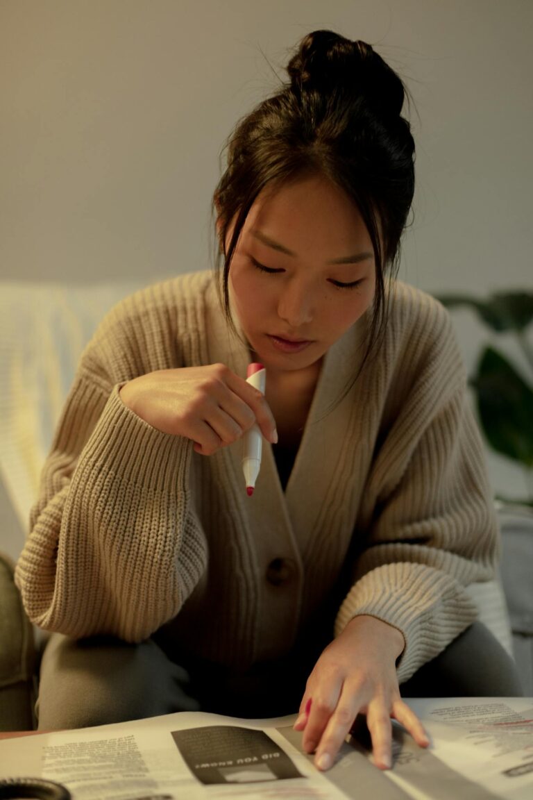 Portrait of black hair woman holding pen and looking for job in newspaper